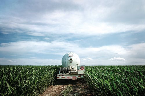 Propane bobtail driver delivers propane in a field