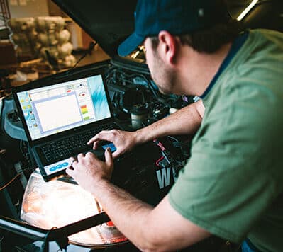A mechanic checking the diagnostics of a propane vehicle on a laptop