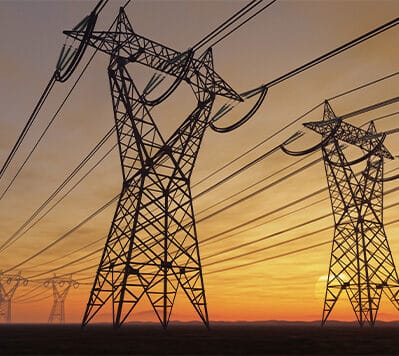 Electrical power lines in a field at sunset