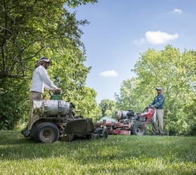 Two members of the Greenwood Group mowing a lawn with propane lawnmowers