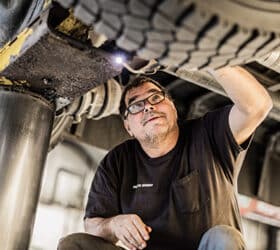 A mechanic working on the underside of a propane school bus