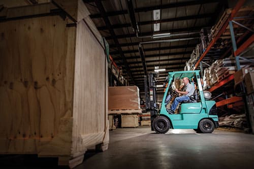 A propane powered forklift lifting a crate