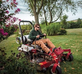 Landscape professional riding a red propane mower