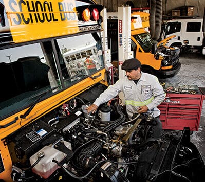 A mechanic working on the engine of a propane autogas school bus
