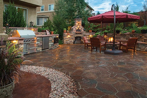 A luxury outdoor living area with a propane outdoor range, fireplace, patio table and other amenities