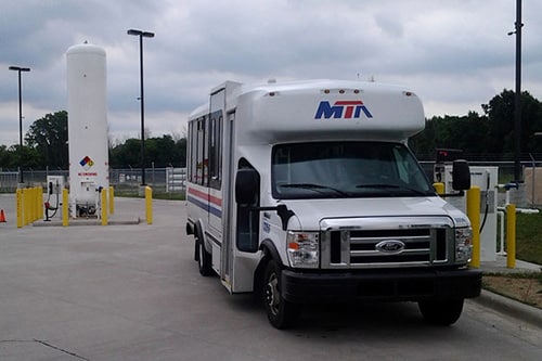 Propane transit van refueling with a propane tank in the background