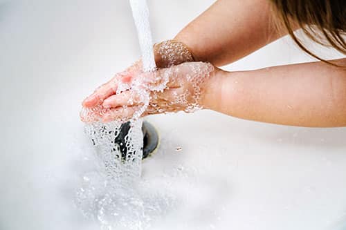 A child's hands under running water from a faucet