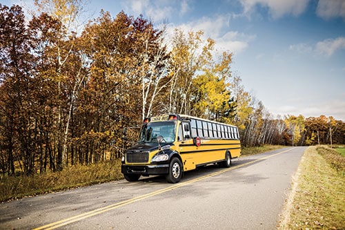 A school bus on a highway in the fall