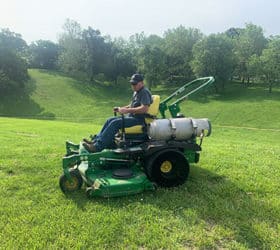 Man riding on a green and yellow propane powered lawn mower