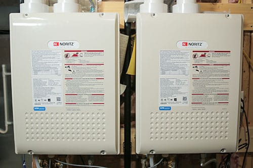 Two tankless water heaters next to eachother on a wall