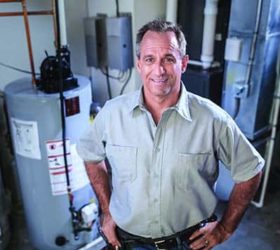 A propane technician in front of water heaters and a furnace